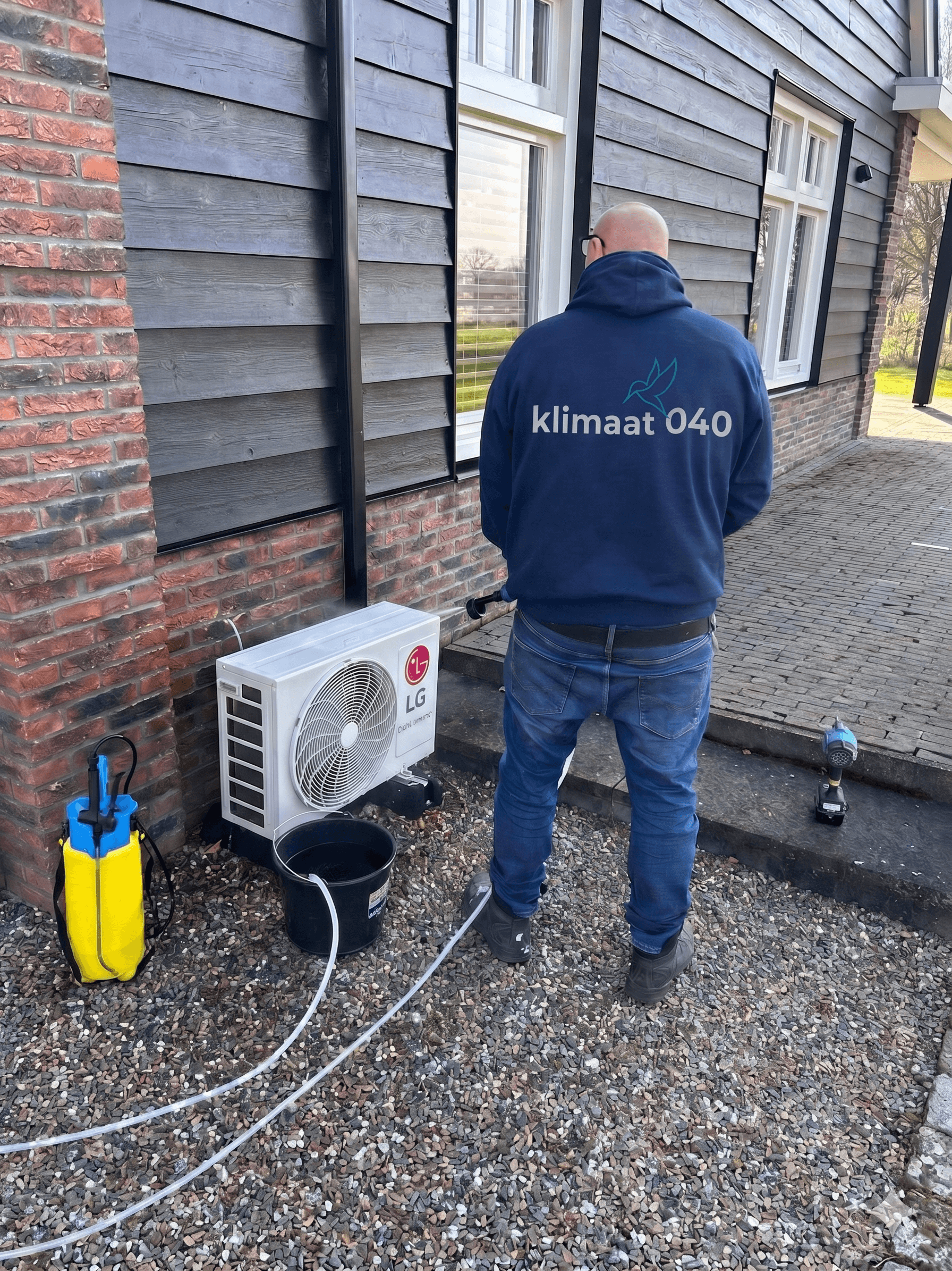 Klimaat 040 monteur reinigt een airco-buitenunit
