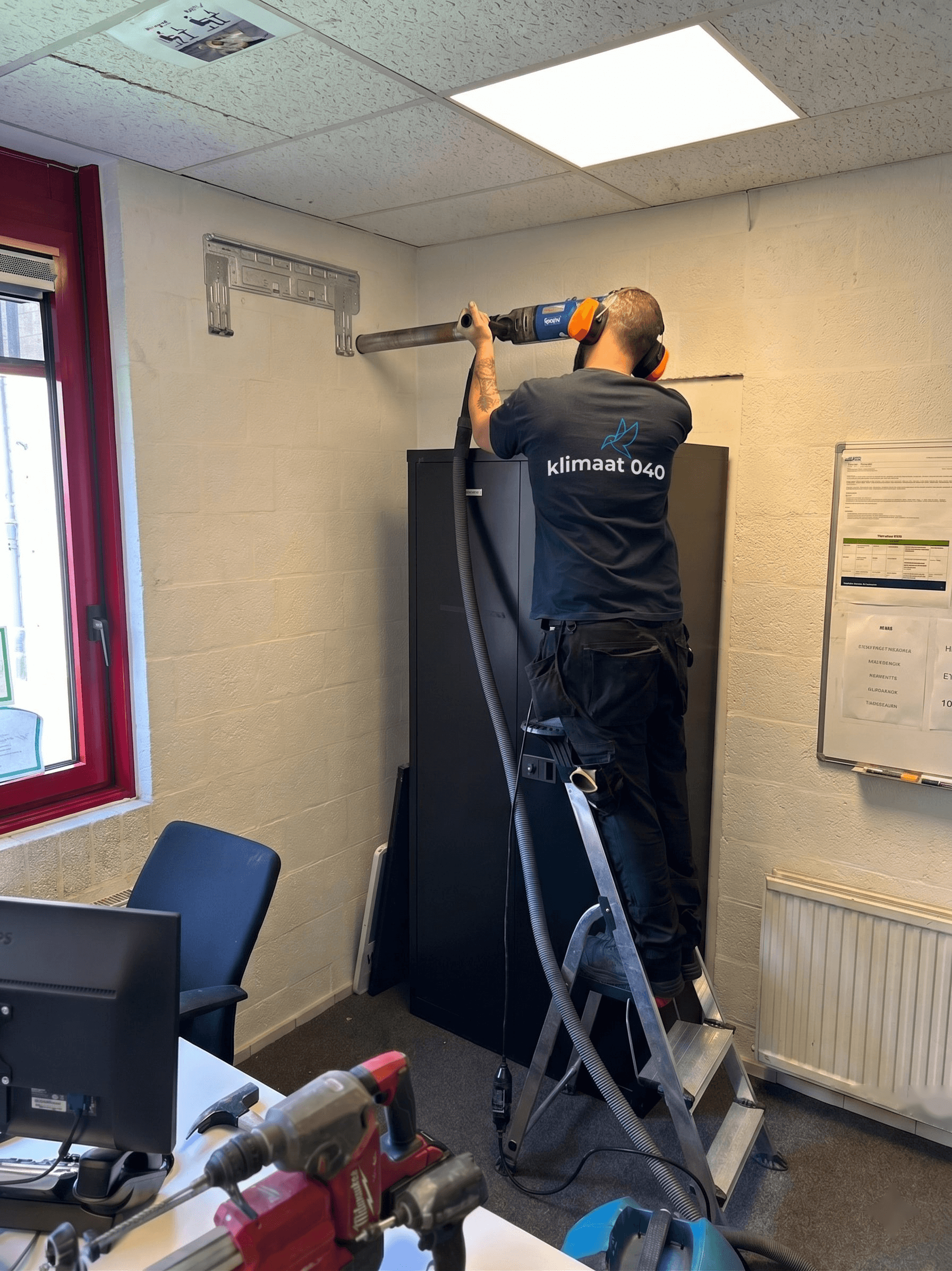 Klimaat 040 monteur boort een doorvoer voor een airco-installatie